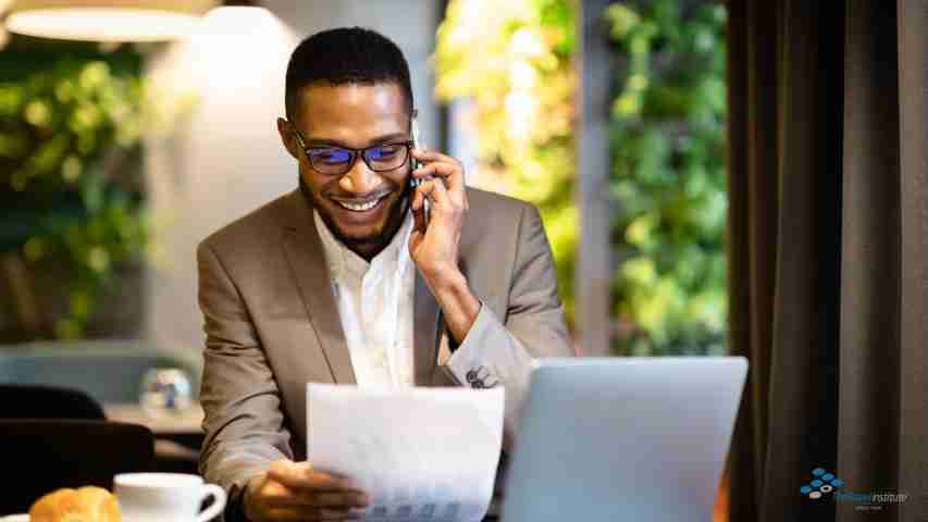 Man talking on a mobile phone and using his computer.