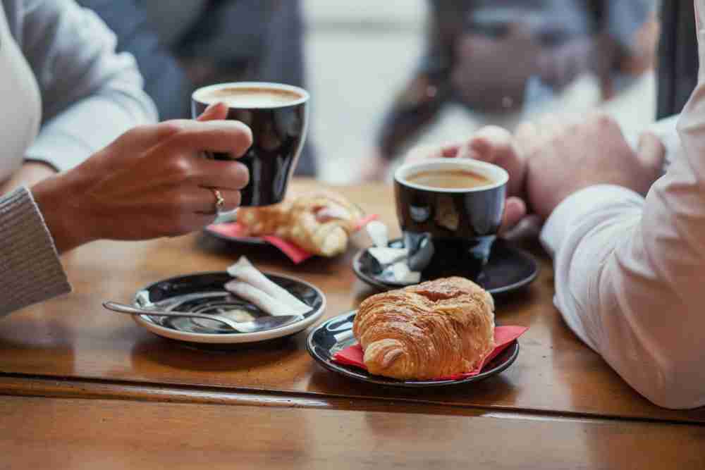 Hands of a couple enjoying croissants and coffee - Song_about_summer/Shutterstock.com