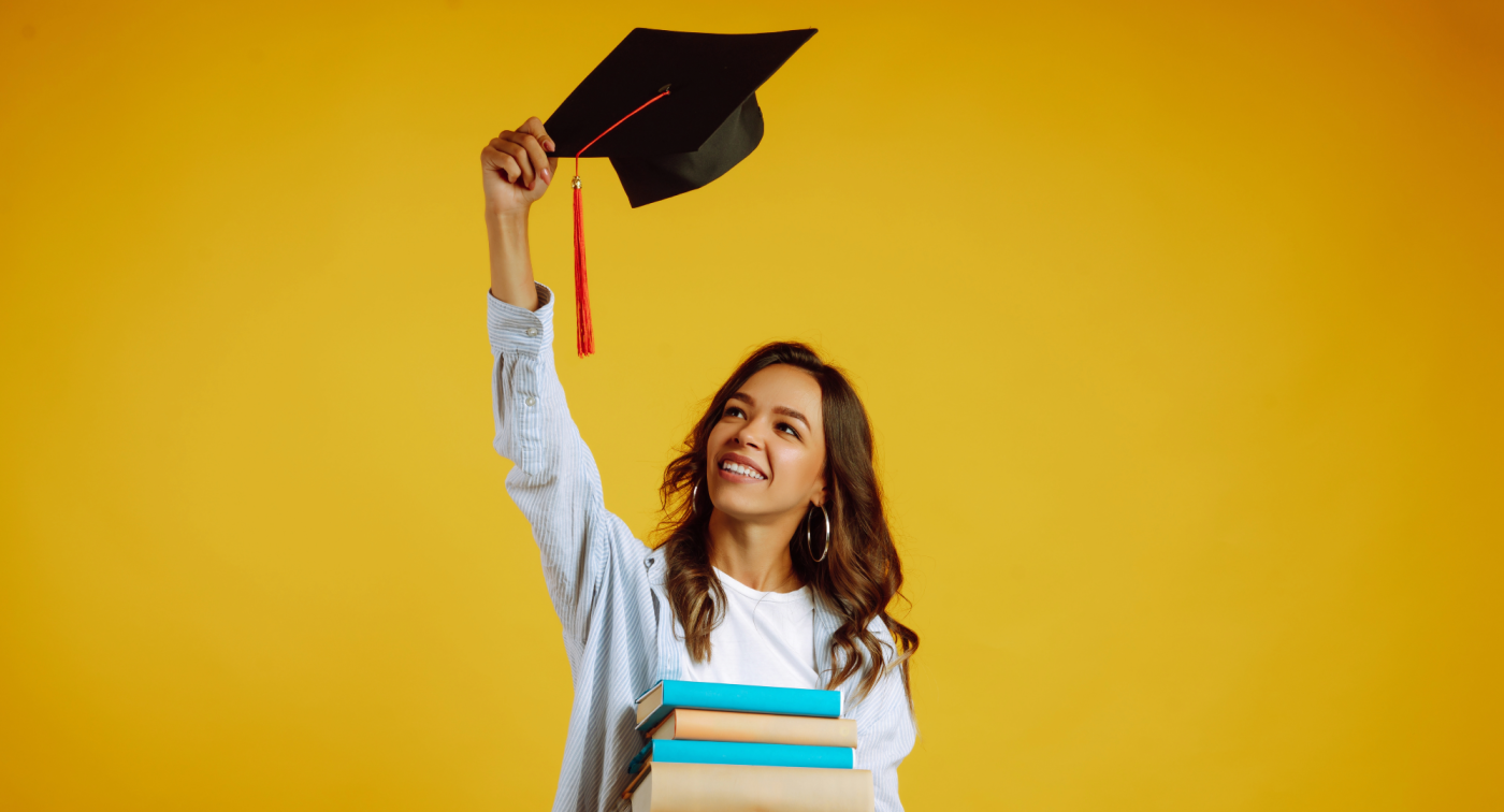 Picture of an attractive young woman raising her graduation cap in the air.
