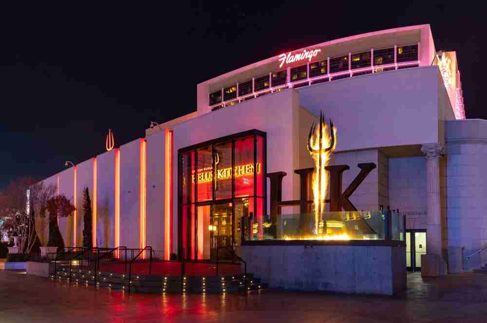Evening exterior view of the Gordon Ramsay restaurant Hell's Kitchen with flaming pitchfork in the entrance.