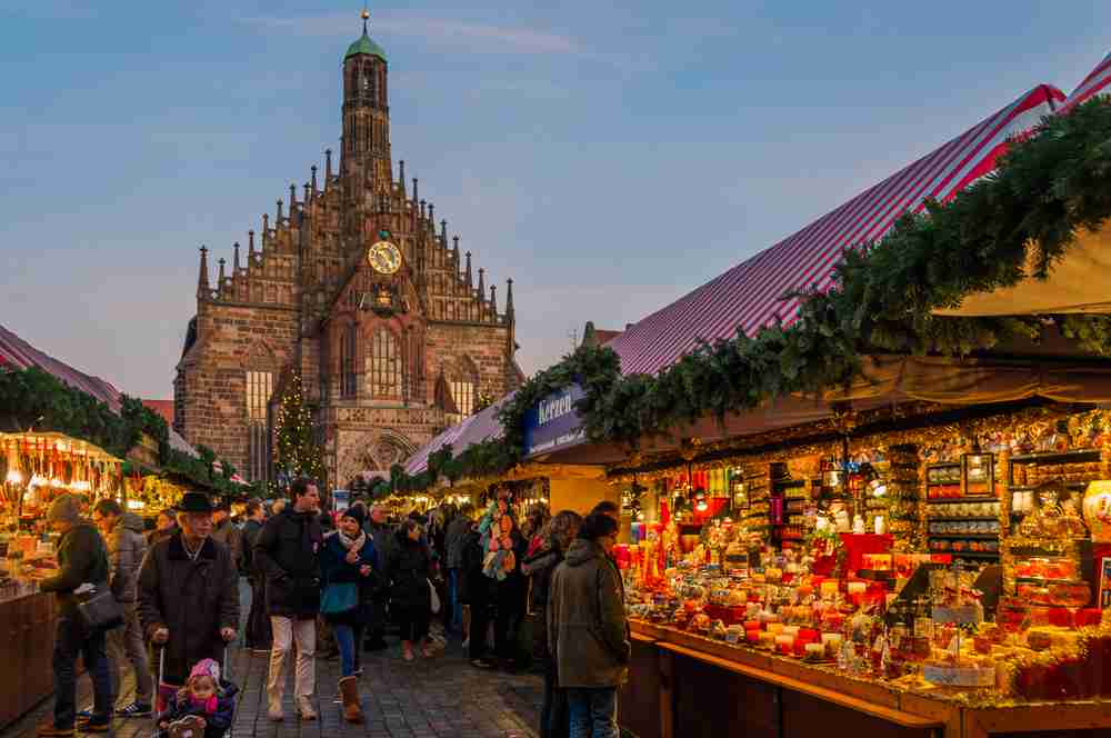Evening view of the Nuremberg Christmas Market - stalls and shoppers with the Cathedral in the background.