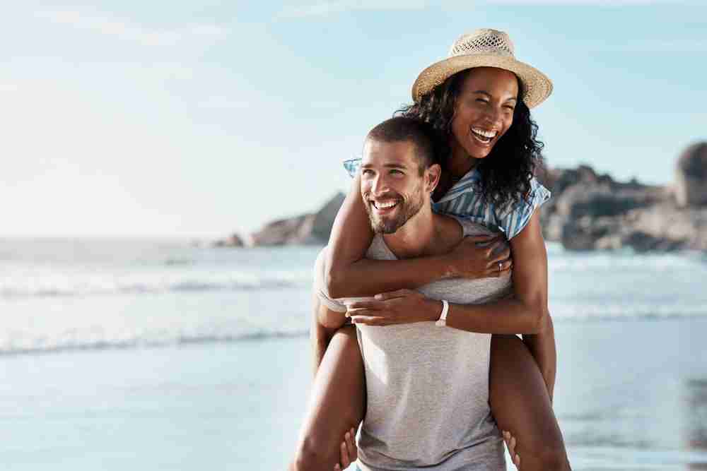 Young, happy couple laughing while on the beach