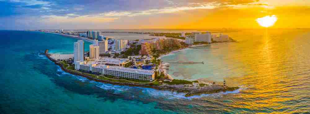 Aerial view of the north point of the Zona Hotelera in Cancun with the sun setting on the right.