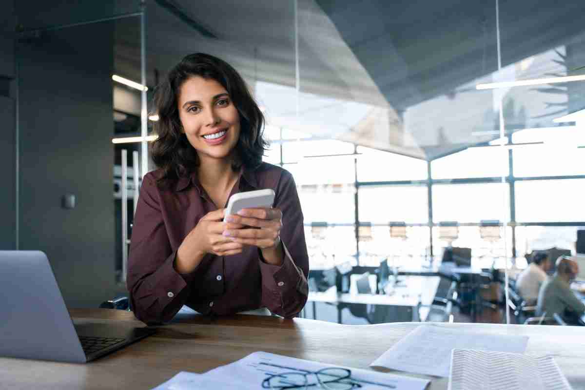 A woman texting on her phone and smiling while at work