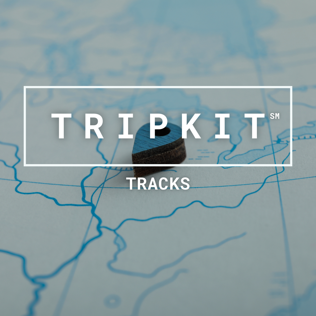 TRIPKIT Tracks. Graphic Words over map with wooden map marker laying on top.