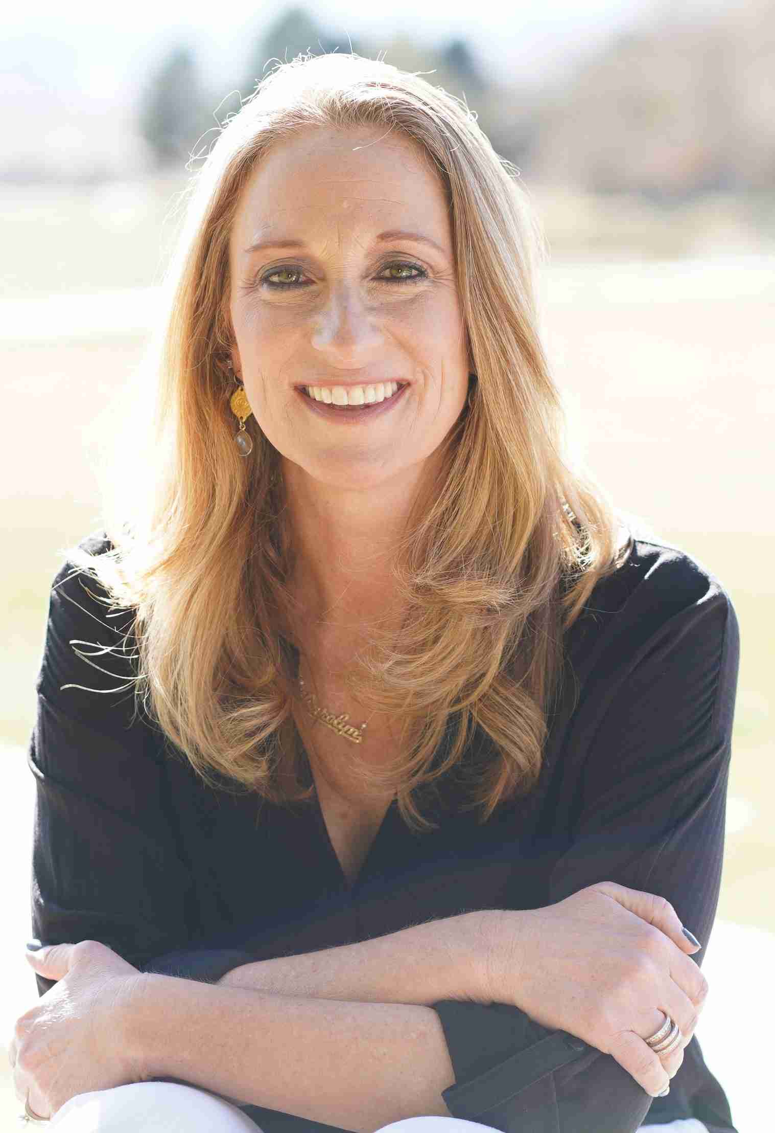 profession photo of Carolyn Orf, CTA. blonde woman in black shirt with arms crossed smiles at camera.